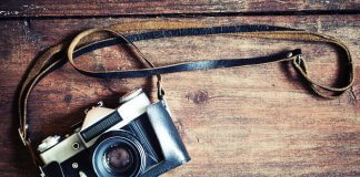 Retro camera on vintage wooden background showing best photography in Iceland concept