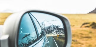 Mountains and road in car rearview mirror in Iceland with times and distances