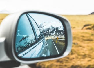 Mountains and road in car rearview mirror in Iceland with times and distances