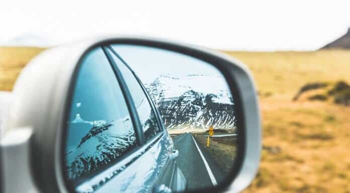 Mountains and road in car rearview mirror in Iceland with times and distances