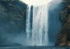 Skogafoss waterfall is imposing over a tourist