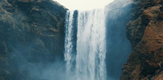 Skogafoss waterfall is imposing over a tourist