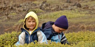 Brother and sister playing in Iceland lava field during family vacation